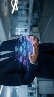 Businessman hand protecting holographic digital network data with glowing connections and circuits in modern office environment for cybersecurity concepts.