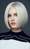 Young Caucasian woman with platinum blonde bob haircut and blue eyes wearing black and white striped top against dark background for fashion and beauty concepts.