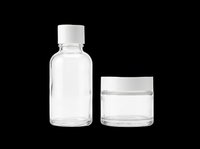 Clear glass dropper bottle and cosmetic jar with white caps, isolated on transparent background, ready for skincare, packaging, and print on demand design use.
