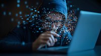 Young male programmer in blue hoodie working on laptop at night with glowing digital particle effect overlay, representing cybersecurity and coding concepts.