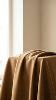 Soft beige fabric draped elegantly in warm natural light creating cozy minimalist interior atmosphere for home decor and textile design projects.