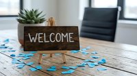 Wooden welcome sign on easel with blue puzzle pieces scattered on rustic table in modern office setting for business greeting concepts.