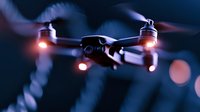 Flying drone with glowing red navigation lights captured in motion against dark background with bokeh effects, modern aerial technology in action.