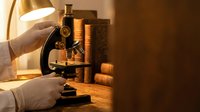 Scientist hands adjusting vintage brass microscope in warm laboratory lighting for medical research and scientific discovery applications.