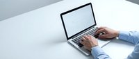 Professional businessman hands typing on modern laptop computer at clean white desk workspace for business productivity and remote work.