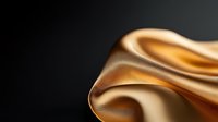 Elegant golden silk fabric with soft waves and folds creating luxurious texture on dark background, macro photography for fashion and luxury design projects.