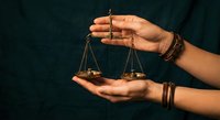 Hands holding golden scales of justice with chains, symbolizing legal balance, fairness and judicial system for law firm branding and legal services.