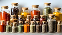 Collection of colorful spices and herbs in glass jars with cork lids arranged on wooden shelf for cooking and seasoning culinary ingredients storage.
