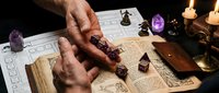 Hands holding wooden dice over ancient spell book with candles and crystals creating mystical tabletop gaming atmosphere for fantasy roleplay adventures.