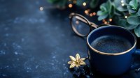 Dark blue coffee cup with golden rim on black stone background with decorative flower and blurred lights, cozy morning atmosphere for social media and blogs.