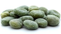Fresh green coffee beans in raw unroasted state on white background, showing natural texture and pattern of coffee seeds before processing.