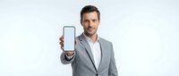 Caucasian male professional in gray business suit displaying blank smartphone screen with white background, suitable for app mockups and corporate presentations.