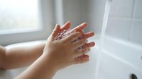 Hands washing under running water with soap bubbles in bright bathroom. Personal hygiene and cleanliness routine for health and wellness care.