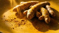 Fresh turmeric roots with golden powder on wooden surface, natural spice ingredient for cooking, health supplements and traditional medicine recipes.
