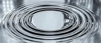 Concentric circular ripples in water create a hypnotic spiral pattern with metallic silver tones, suitable for backgrounds and abstract designs.