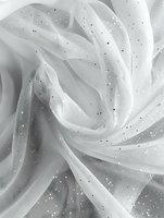 Delicate white tulle fabric with glitter sparkles creates soft flowing folds and textures, capturing ethereal light and shadow for wedding and formal designs.