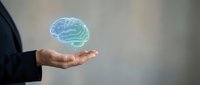 Businessman holding glowing blue brain hologram in open palm representing artificial intelligence, innovation, creativity and mental health concepts.