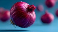 Fresh red onion with papery skin on blue background, organic vegetable for cooking and culinary preparations in kitchen.