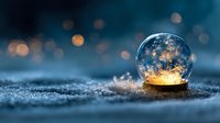 Magical crystal ball with glowing golden light on frosty surface against blurred bokeh background, creating mystical winter atmosphere.