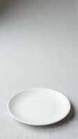 Empty white ceramic plate on neutral gray surface, suitable for food styling, restaurant menus, and tableware design projects.