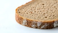 Fresh whole grain bread slice with rustic crust on white background, isolated for healthy breakfast and sandwich preparation concepts.