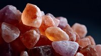 Pink Himalayan salt crystals in macro view showing natural mineral texture and rough crystalline structure against dark background.