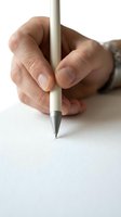 Close-up of a hand holding a pen on white paper, ready to write or sign a document, capturing focus and precision.