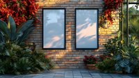 Blank black frames on brick wall surrounded by lush tropical plants and vibrant red bougainvillea flowers, sunset light casting soft shadows through windows.