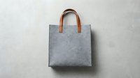 Gray felt tote bag with brown leather handles isolated on white background, suitable for product mockups, branding, retail displays, and e-commerce presentations.
