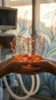 Hands holding glowing orange network sphere with connected nodes representing digital technology, artificial intelligence, and global communication in modern office environment.
