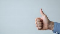 Male hand showing thumbs up gesture against clean white background for business success and approval concepts.