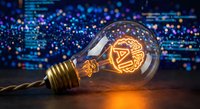 Glowing light bulb with circuit board filament on wooden surface against blurred digital technology background for innovation and creativity concepts.