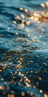 Sparkling sunlight creates magical golden bokeh effect on rippling blue ocean water surface, capturing ethereal interplay of light and movement at sunset.