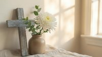 Rustic wooden cross with white chrysanthemum flower in ceramic vase on linen fabric, soft natural lighting creates peaceful spiritual atmosphere for home decor.