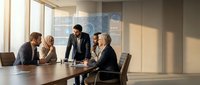 Professional business team meeting in modern conference room with natural lighting and presentation materials for corporate strategy discussion.