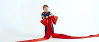 Young caucasian boy child playing superhero with flowing red cape on white background isolated for design and clipart use in costumes and play concepts.