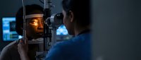 Male patient undergoing comprehensive eye examination with slit lamp microscope by ophthalmologist in modern medical clinic for vision health assessment.