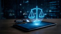 Digital justice scales hologram emerging from tablet screen with eyeglasses on wooden desk against blurred city lights background for legal technology concepts.