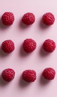 Fresh ripe raspberries arranged in rows on pink background creating geometric pattern. Natural organic berries with soft shadows for food design.