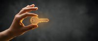 Close-up of hand holding glowing golden key against dark background, symbolizing success, opportunity, solution, and unlocking potential for business and security concepts.