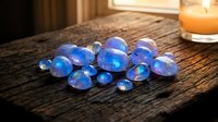 Blue iridescent glass marbles scattered on rustic wooden surface with warm candlelight creating magical atmosphere for home decor and relaxation concepts.