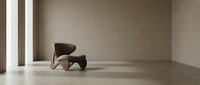Modern brown sculptural chair in minimalist gallery space with polished concrete floor and neutral walls.