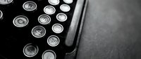 Vintage typewriter keys in black and white showing classic round buttons with letters and symbols on dark textured surface for retro office design projects.
