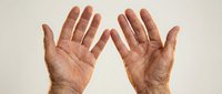 Elderly hands with visible wrinkles and age spots raised up showing palms in surrender or stop gesture against neutral background for healthcare concepts.