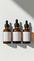 Amber glass dropper bottles with blank white labels on white background with natural shadows. Mockup for essential oils, serums, or cosmetic products.