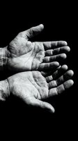 Two weathered open palms facing up against dark background, black and white dramatic close-up showing life lines, wrinkles, and hard work.