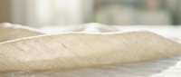 Woven textile fabric with natural beige tone and diagonal weave pattern, isolated on white background for design and craft projects.