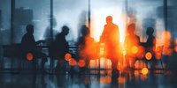 Business meeting silhouettes against bright window light in modern office conference room with city skyline view during sunset or sunrise hours.