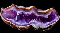 Stunning amethyst geode cross-section displaying vibrant purple crystal formations with natural banding patterns on black background for geology education.