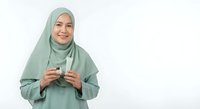 Young Muslim woman in green hijab holding coffee cup smiling warmly on white background isolated for design use in lifestyle marketing materials.